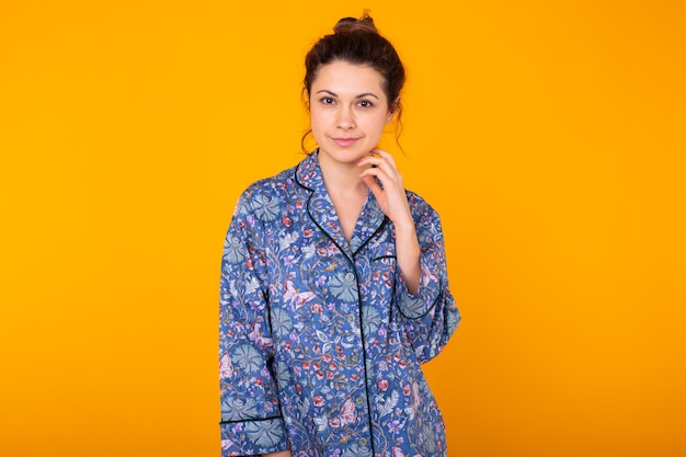 Girl in pajamas posing while resting at home on yellow background