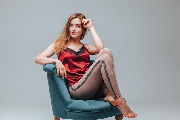 Girl in pajamas sitting on a chair on a gray background