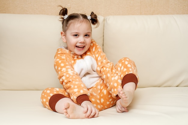 Girl in pajamas sitting on the couch, smiling