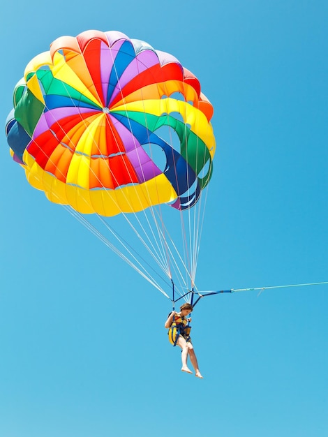 Girl parascending on parachute in blue sky