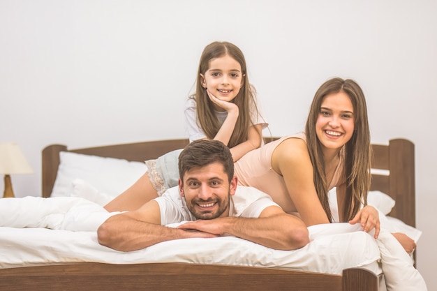 The girl and parents lay on the bed