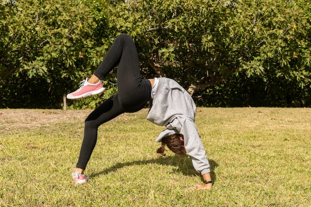 Una ragazza nel parco che fa esercizi acrobatici giocando all'aperto e impegnandosi in attività di ginnastica