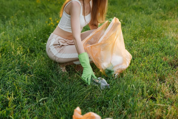 Девушка в парке на закате занимается сбором мусора в парке Забота об окружающей среде Переработка отходов Сортировка мусора