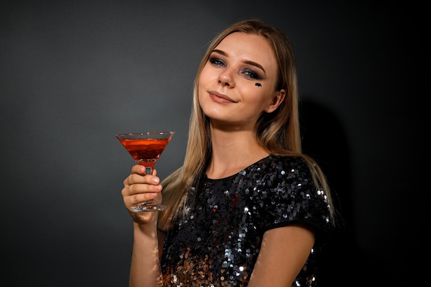 A girl at a party in the style of Halloween with a cocktail in her hands