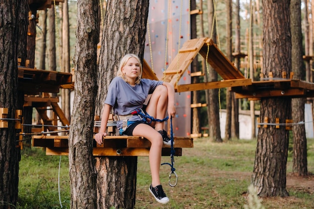 A girl passes an obstacle in a rope town A girl in a forest rope park