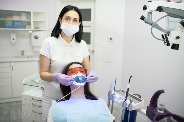 Girl patient in the dental clinic Teeth whitening UV lamp with photopolymer composition