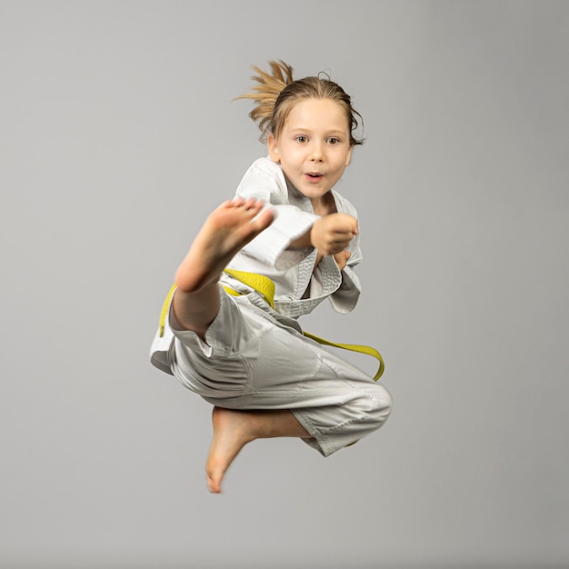 girl performs martial arts flying kick studio shot