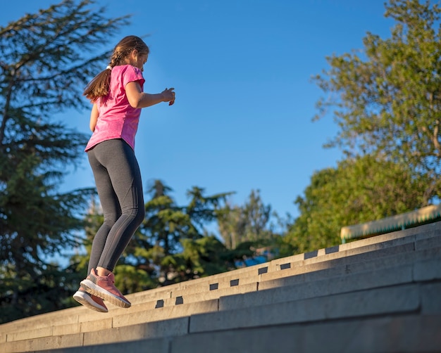 the girl performs physical exercises and jumps up the stairs