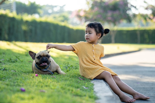 A girl petting a pug dog in a park