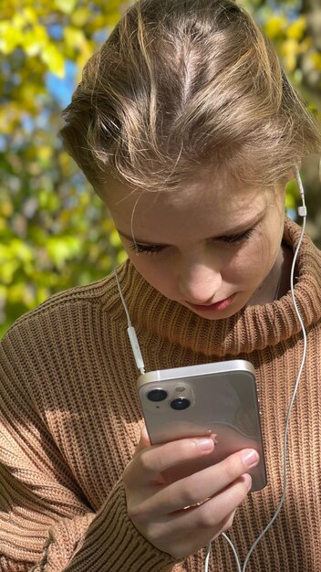 Girl phone headphones forest beige sweater