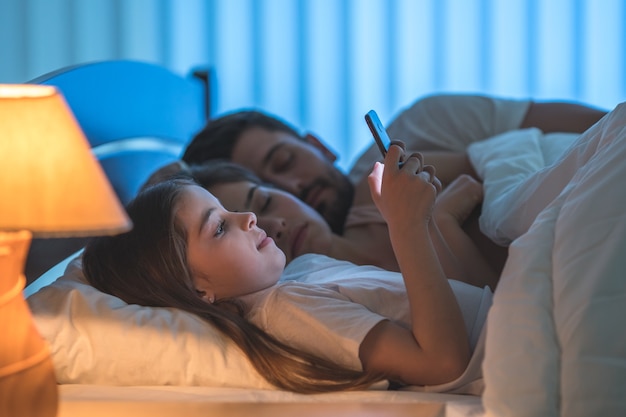 The girl phone near the sleeping parents. night time