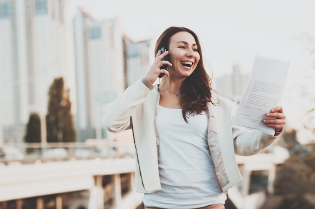 Girl on phone, papers with buildings on background