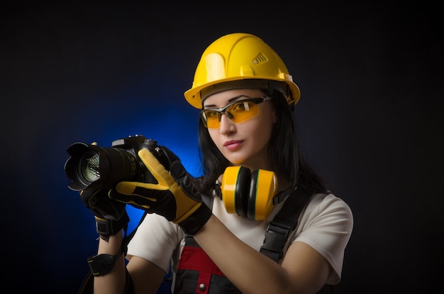 The girl photographer at a construction site in a helmet with a DSLR camera