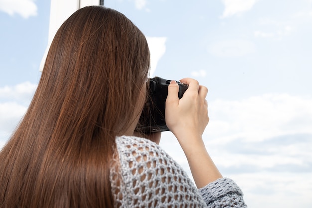 女の子の写真家は窓から風景を撮ります