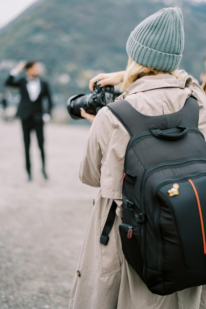 Girl photographer takes photos with a digital camera back view