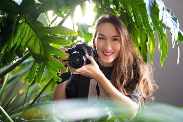 Girl photographer with camera smiling while traveling in wild jungle