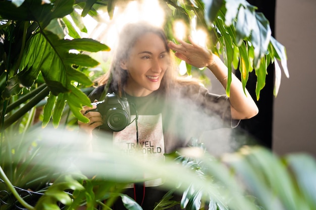 Girl photographer with camera smiling while traveling in wild jungle