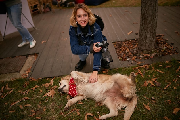 犬の女の子と女の子の写真家は犬をなでるデニムジャケットで犬の女の子と遊ぶ