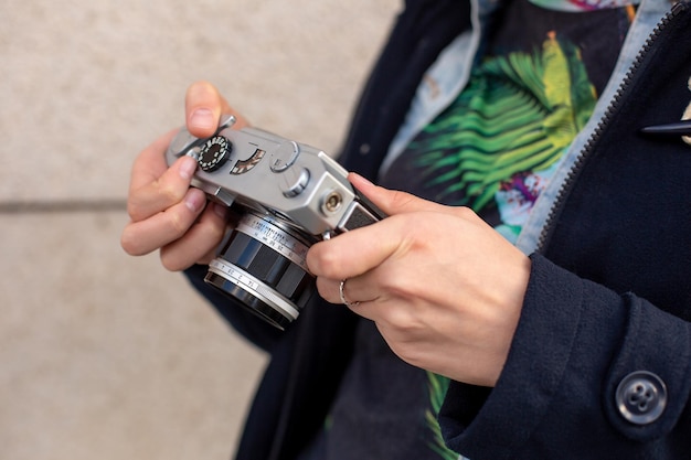 Девушка-фотограф со старой камерой в руках. Стильный модный фотограф на городской улице