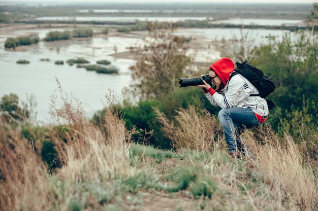 Photo girl photographing nature standing on the edge of the cliff