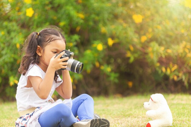 Girl photographing toy while sitting on land