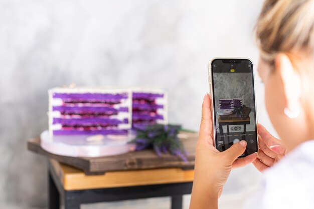 Foto una ragazza fotografa una torta con il suo smartphone