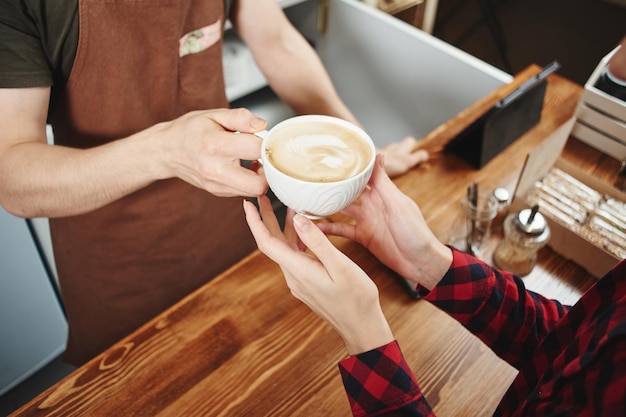 女の子はバリスタからコーヒーを拾います。手とカップのクローズアップ