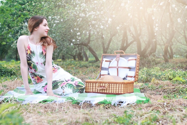 Girl on a picnic in the apple orchard with a basket of products