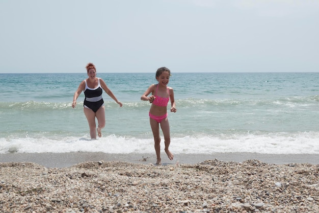 Girl in a pink bikini playing happily on the shore of the beach with her mother on a sunny summer day Vera Spain