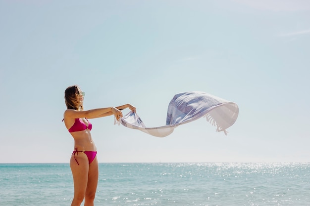 Girl in a pink bikini with a towel at the beach