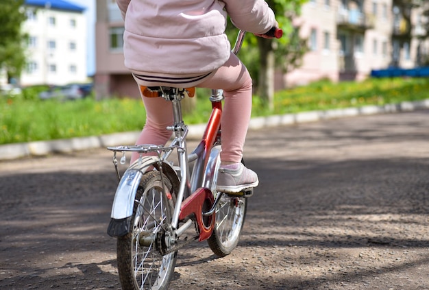 Девушка в розовой одежде на велосипеде по дороге.