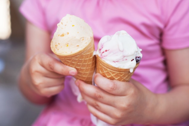 Girl in pink dress eating ice cream in hot weather