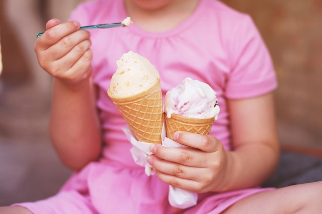 Girl in pink dress eating ice cream in hot weather