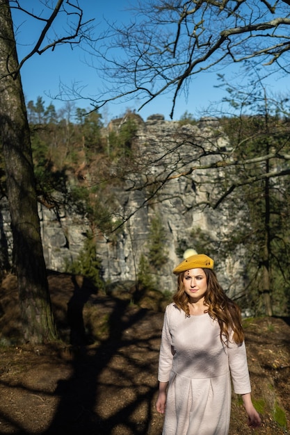 A girl in a pink dress and hat on the background of mountains and gorges in Swiss Saxony, Germany, Bastei.