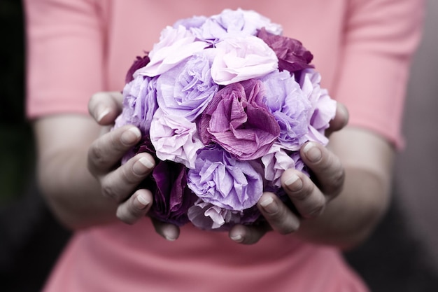 The girl in a pink dress holding a bouquet of purple flowers