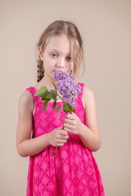 Photo a girl in a pink dress holds a bouquet of lilac flowers.