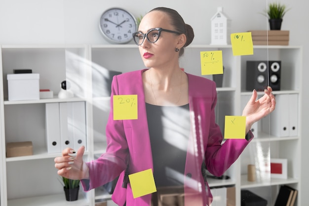 a girl in a pink jacket holds a board with stickers