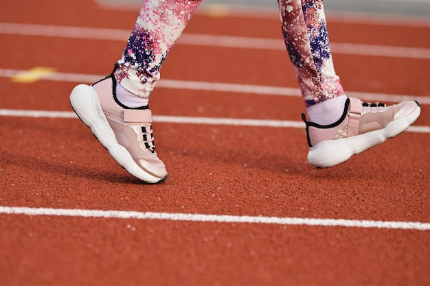 Girl in the pink sneakers runs in the stadium