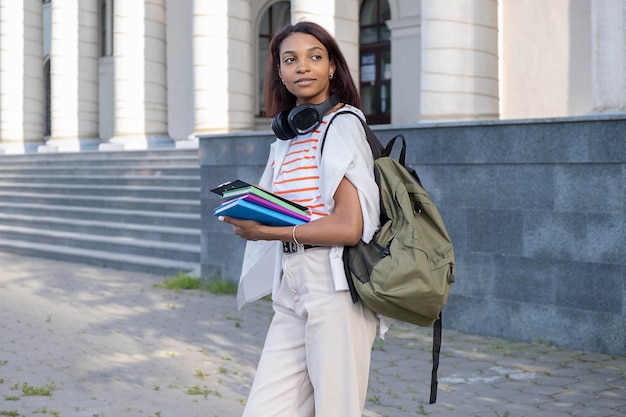 A girl in a pink tshirt holding textbooks in her hands