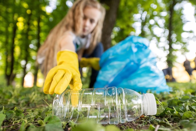 Ragazza alla raccolta dei rifiuti di plastica in un parco