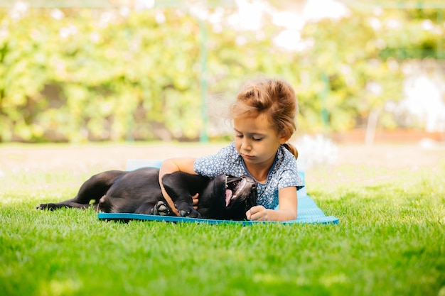 Girl play with adorable black labrador puppy