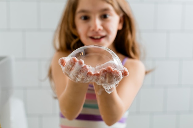 Girl playing in the bathroom making big soap bubbles