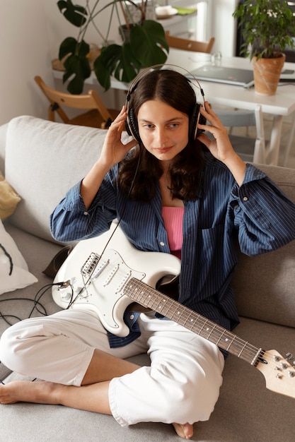 Foto ragazza che suona la chitarra a casa ad alto angolo