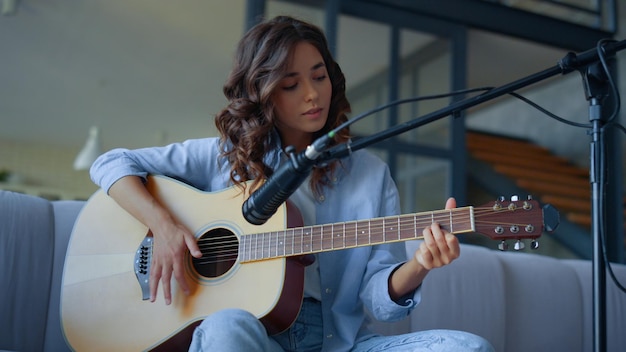 Girl playing guitar at home recording studio Musician recording sound of guitar