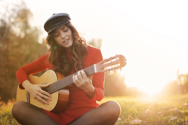 Girl playing on a guitar in the park