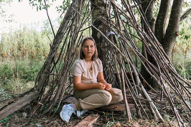 Girl playing in a hut made of twigs and leaves. wooden house in the village