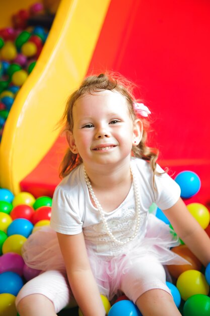 Девочка играет на детской площадке, в детском лабиринте с мячом