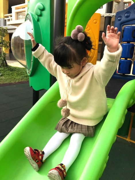 Foto ragazza che gioca sullo scivolo nel parco giochi