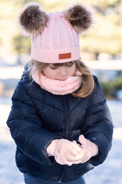 雪の中で遊ぶ女の子が雪片を作る