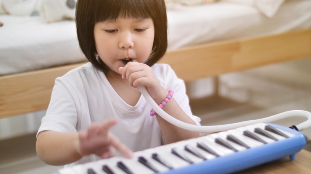 写真 家でおもちゃのピアノを弾いている女の子